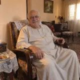 A grandfather at home, holding a glass of tea